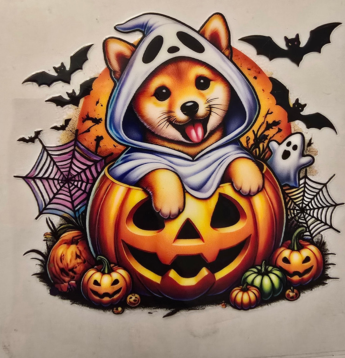 Halloween puppy in ghost costume with pumpkin